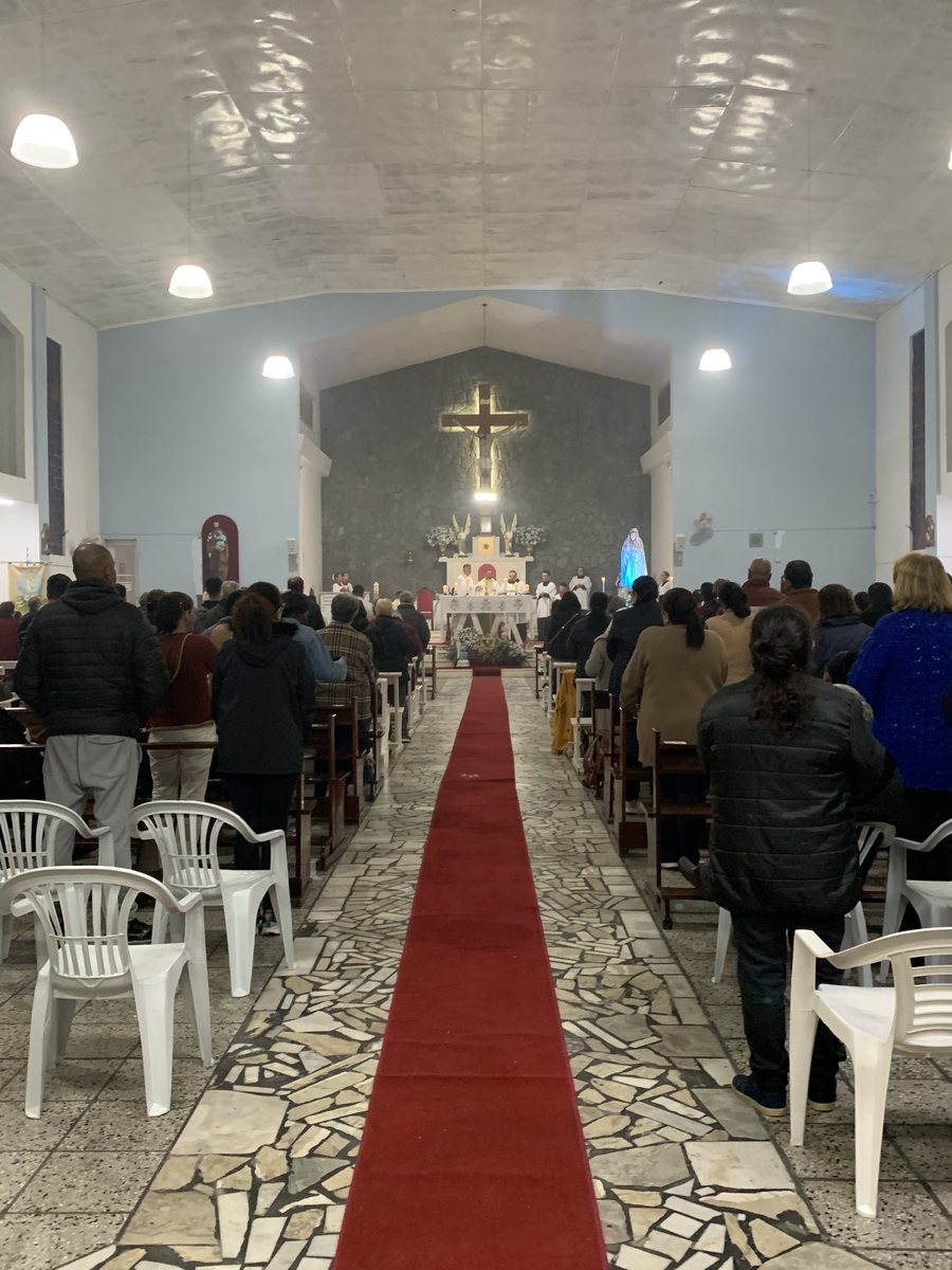 Corredor central da igreja com tapete vermelho e a igreja cheia de fiéis